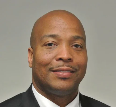 Kelvin Sellers in a suit and tie poses for a professional headshot against a plain background.